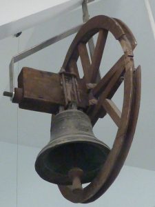 A large bell attached to a wheel mechanism used to make it ring. 