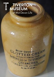 A beige earthenware container printed with black text that reads 'Best Devonshire Clotted Cream direct from the Duchess of Devonshire Creameries. Tiverton Junction, Devon'.